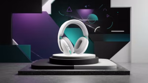 White over-ear headphones with teal accents displayed on a circular pedestal against a geometric studio backdrop in a product shot.