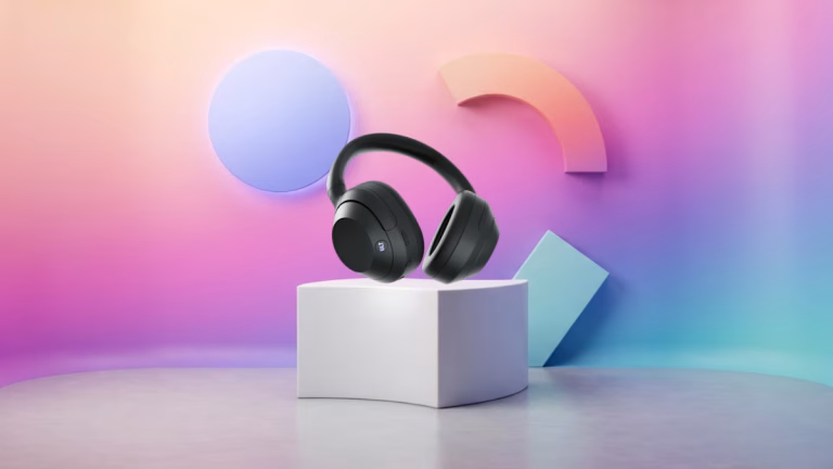 Black over-ear headphones resting on a white cube pedestal against a pastel gradient backdrop with geometric shapes in the background, product shot